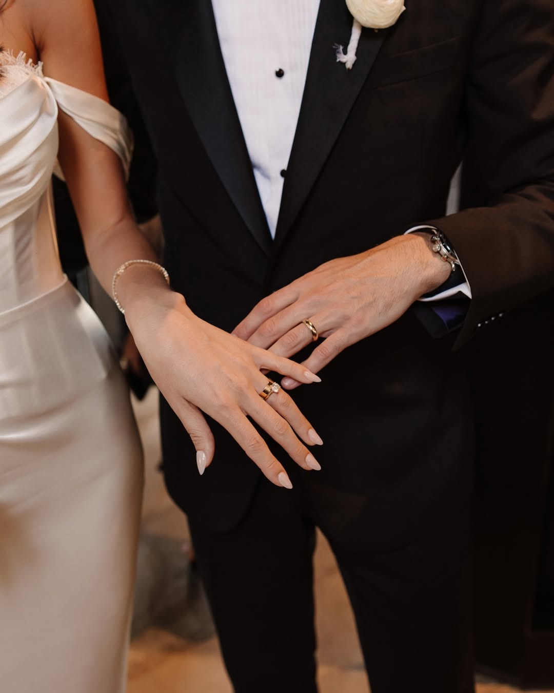 Bride and groom showing their wedding rings, hands resting together